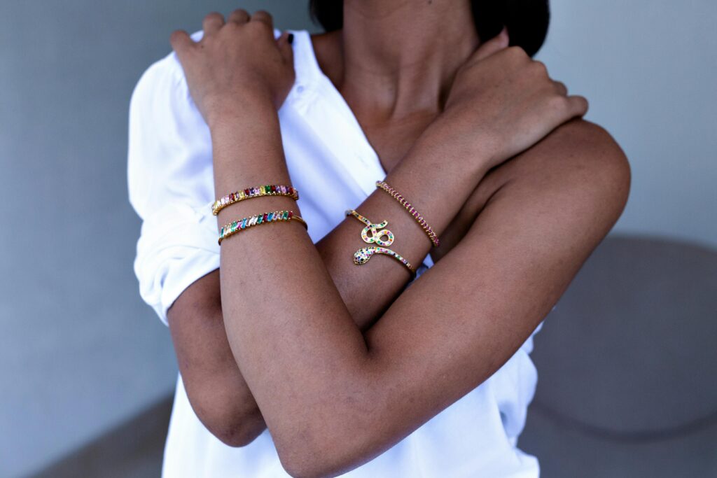 Close-up of a woman's crossed arms adorned with colorful gemstone bracelets, showcasing elegance and style.
